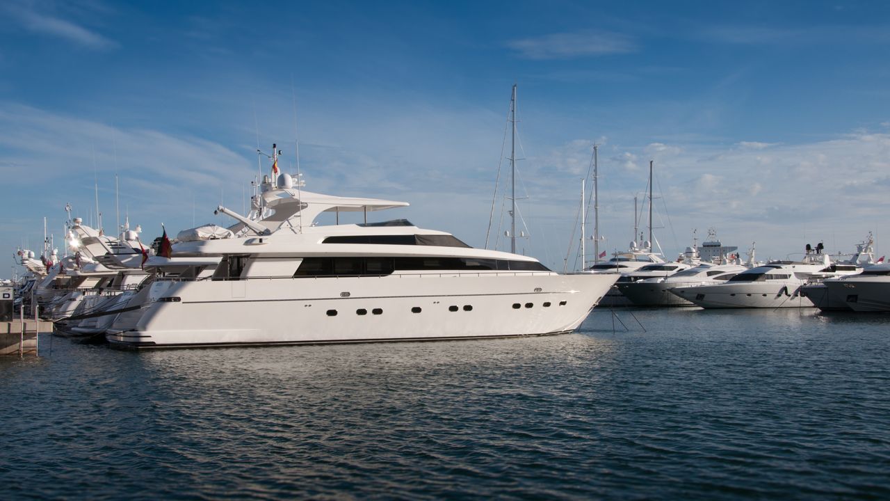 A white motor yacht moored among other boats in a shipyard basin